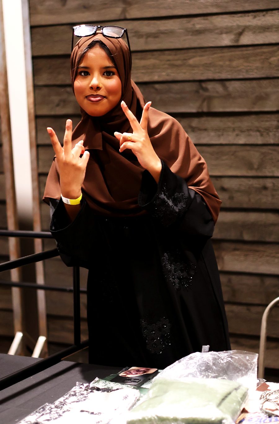 A vendor smiling and waving from behind her table